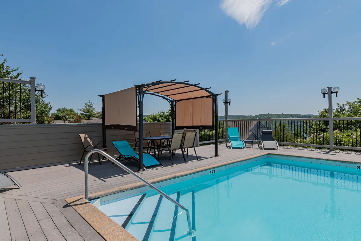 A vibrant exterior shot of a swimming pool area with a cabana, lounge chairs, and a scenic backdrop. The inviting poolside setting encourages relaxation and socializing, complementing the amenities available to guests after a day on the lake.