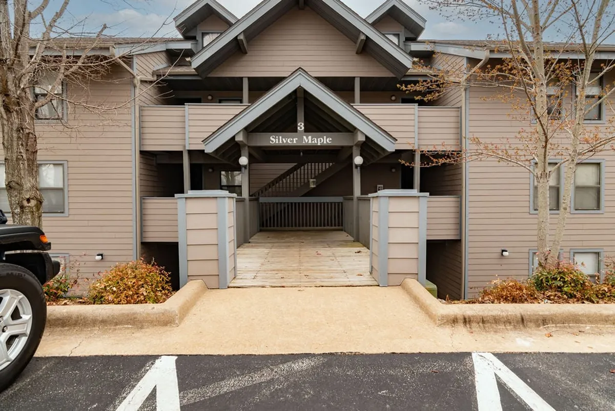 The welcoming entrance marked 'Silver Maple' features a wooden walkway surrounded by lush trees, creating a sense of arrival and connection to the natural beauty of the area. The sign signals the start of a community experience tied closely to the outdoors.
