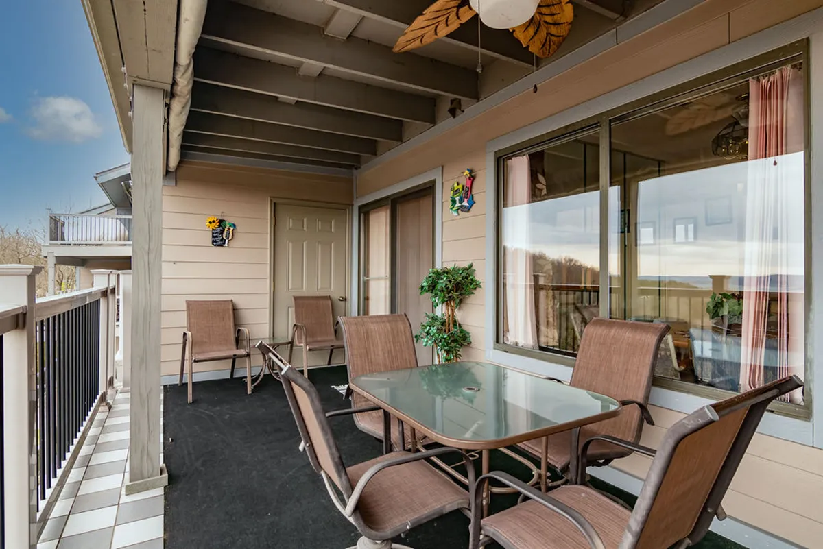 This image shows a welcoming exterior dining area set with a table and chairs, surrounded by lush green plants and decorative wall art. The setting is ideal for outdoor dining or socializing with friends, with sunset views that create a warm and inviting atmosphere.
