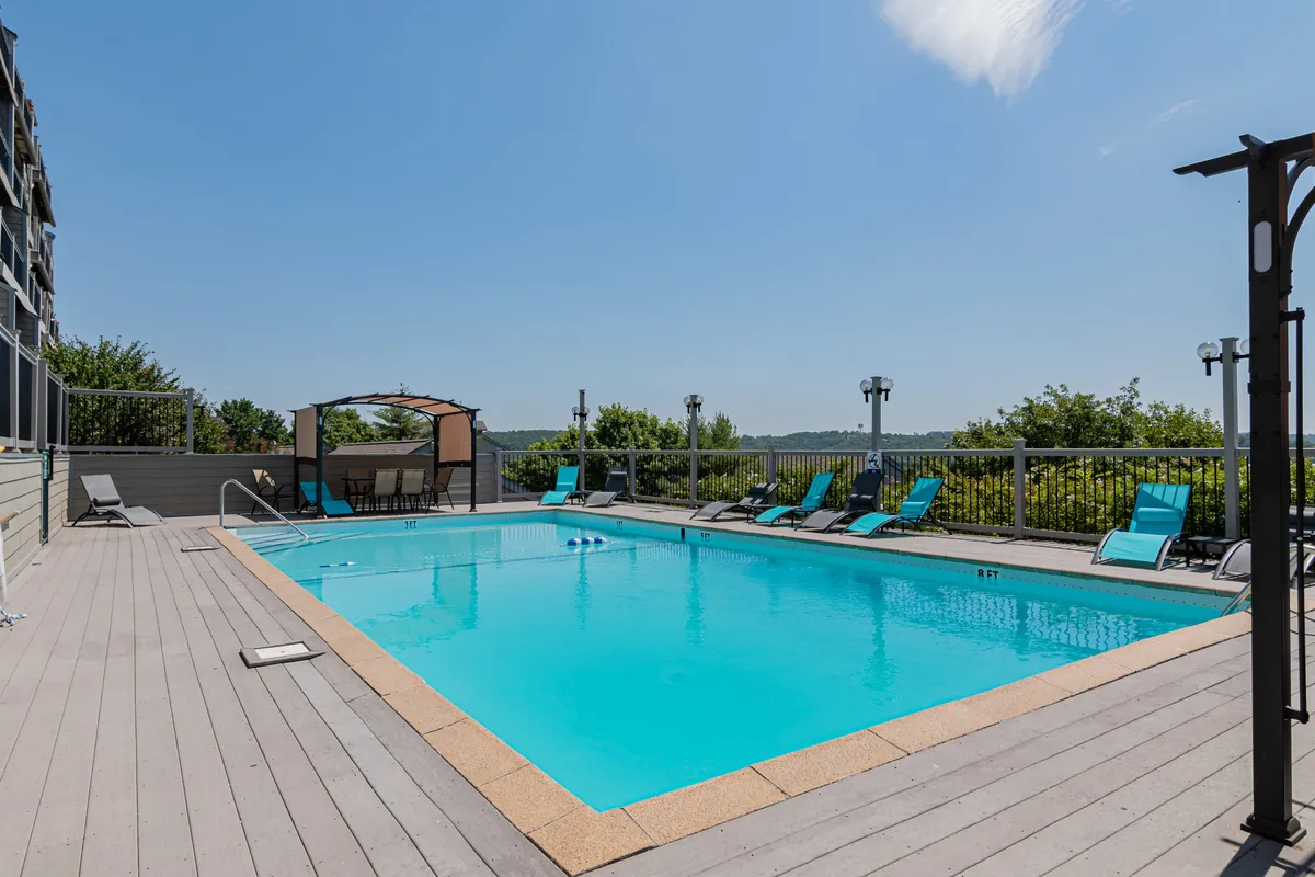 This image features a sparkling swimming pool surrounded by lounge chairs and a cabana, all set in a lush outdoor environment. The inviting pool area offers ample space for relaxation, swimming, and family fun under the sun.
