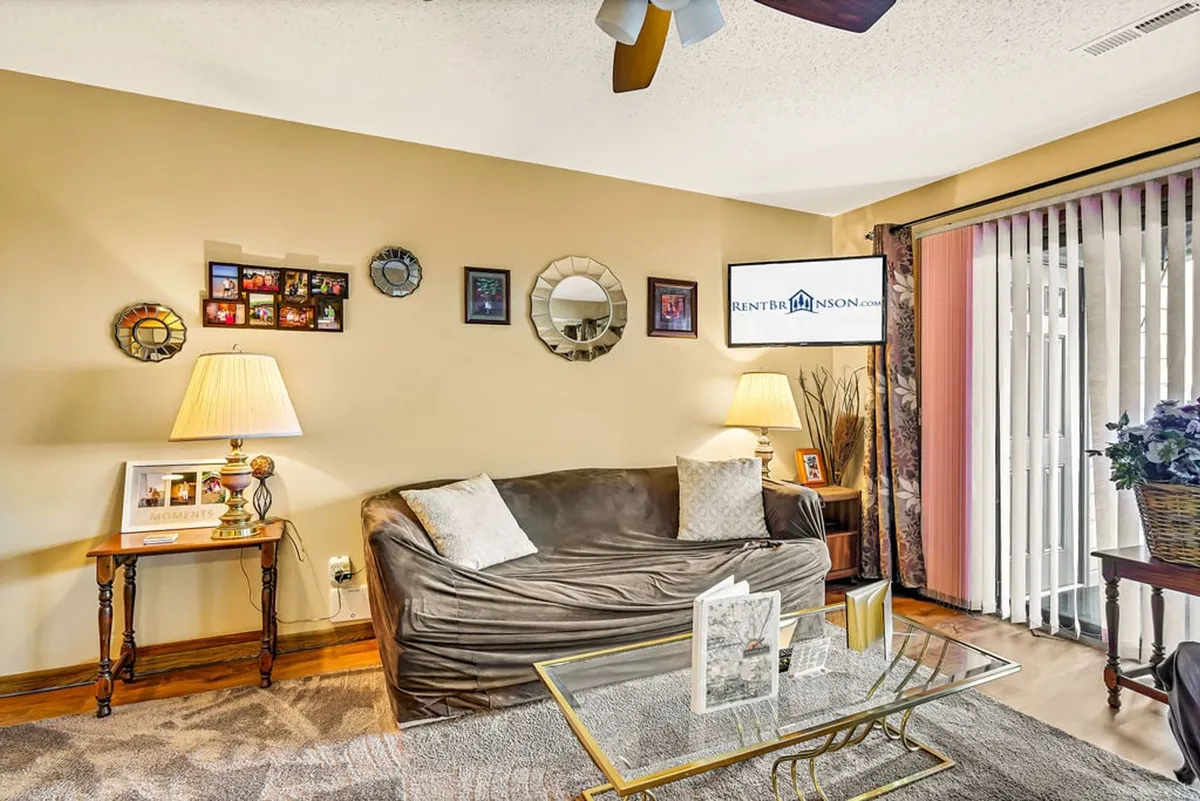 A cozy, classic-inspired living area featuring a plush sofa, coffee table, lamps, decorative wall art, and a television. The space is warmly lit and inviting, ideal for relaxing or gathering for a family movie night after a fun-filled day.