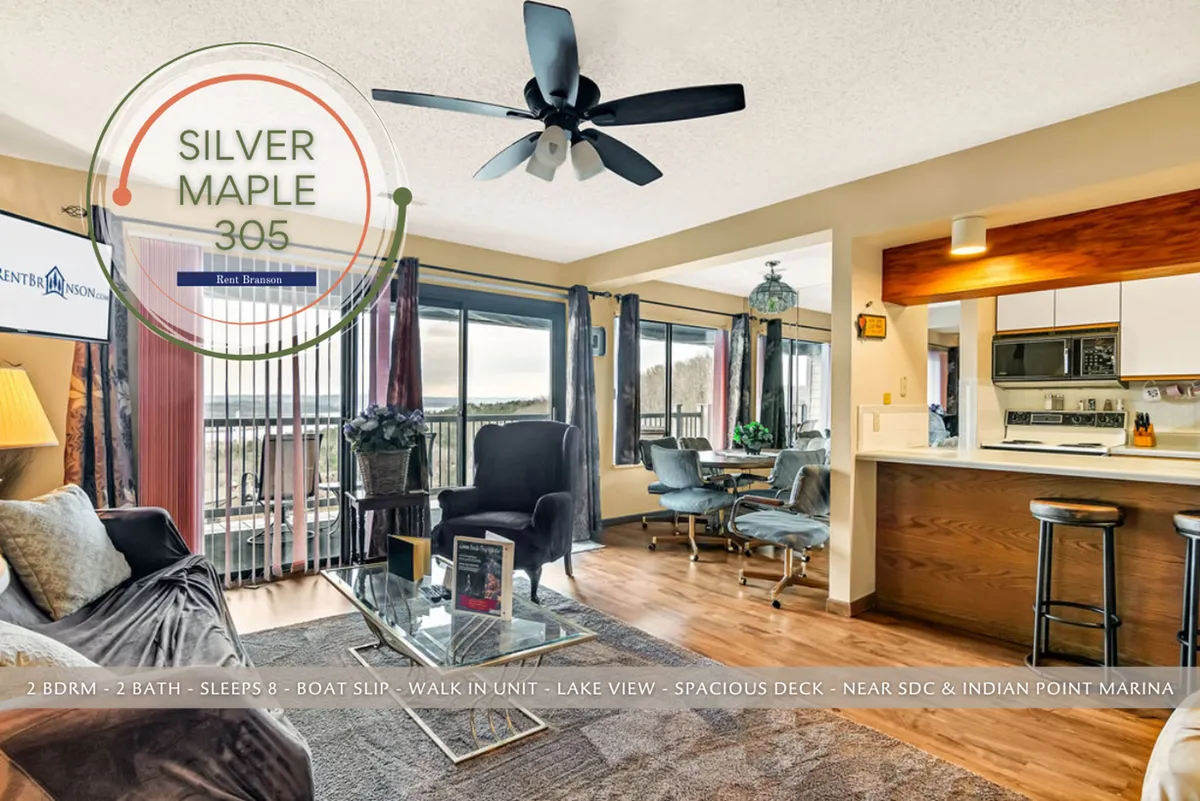 A spacious, open-concept living area with comfortable seating oriented toward large windows that offer a stunning panoramic view of Table Rock Lake. Visible is a seamless transition to an extra-large private deck, ideal for entertaining or relaxing while enjoying the outdoors.