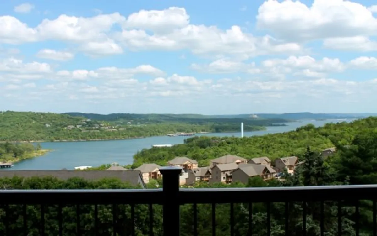 A panoramic view of Table Rock Lake, framed by lush greenery, distant hills, and a peaceful sky. The image evokes a sense of tranquility and the beauty of nature just steps from the property, inviting outdoor exploration and adventure.